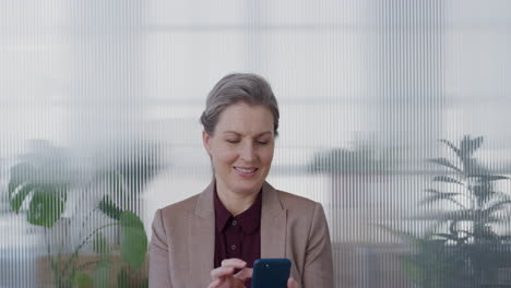 portrait-successful-senior-business-woman-boss-using-smartphone-enjoying-browsing-online-messages-texting-on-mobile-phone-smiling-satisfaction-slow-motion