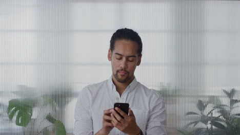 portrait-handsome-young-hispanic-businessman-using-smartphone-in-office-browsing-messages-working-sending-emails-on-mobile-phone-texting-looking-pensive-slow-motion-digital-communication