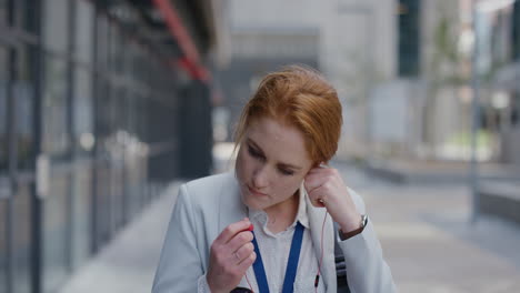 portrait-attractive-young-red-head-business-woman-intern-puts-on-earphones-listening-to-music-in-city-enjoying-relaxed-urban-lifestyle-professional-caucasian-female-commuting