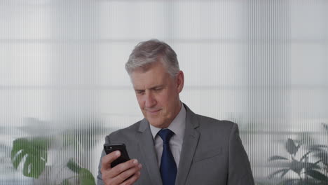 portrait-happy-mature-businessman-executive-using-smartphone-enjoying-texting-browsing-messages-sending-email-sms-on-mobile-phone-in-office-slow-motion
