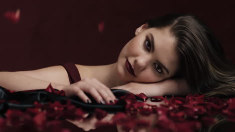 Porträt-Einer-Schönen-Kaukasischen-Frau,-Die-Mit-Fallenden-Rosenblättern-Spielt,-Sinnliche-Frau,-Die-Von-Intimer-Fantasieromantik-Träumt-Und-Dem-Verlangen-In-Rotem-Hintergrund-Valentinstagskonzept-Frönt