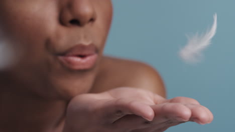 slow-motion-young-african-american-woman-blowing-feathers-falling-on-hand-skincare-concept-close-up