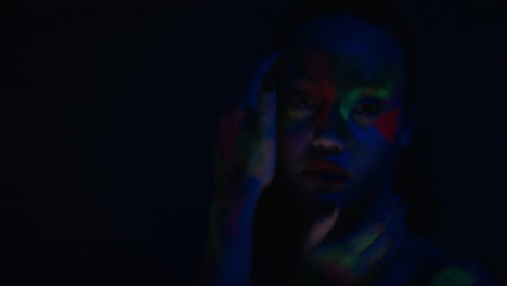 Nahaufnahme-Eines-Farbenfrohen-Porträts-Einer-Attraktiven-Frau-Mit-Fluoreszierender-Gesichtsbemalung,-Exotischer-Mehrfarbiger-Körperkunst-Mit-Blinkendem-UV-Licht,-Extremem-Make-up-Konzept