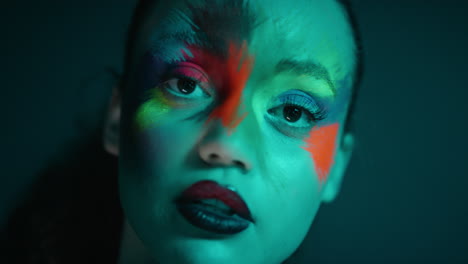 Nahaufnahme-Eines-Farbenfrohen-Porträts-Einer-Attraktiven-Frau-Mit-Fluoreszierender-Gesichtsbemalung,-Exotischer-Mehrfarbiger-Körperkunst-Mit-Blinkendem-UV-Licht,-Extremem-Make-up-Konzept