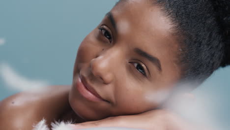 Nahaufnahme-Eines-Porträts-Einer-Schönen-Jungen-Afroamerikanischen-Frau,-Die-Entspannte-Federn-Auf-Weicher,-Natürlicher-Haut-Fallen-Lässt-Und-Sanft-Einen-Gesunden-Teint-Im-Zeitlupen-Hautpflegekonzept-Streichelt