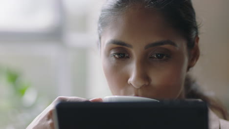 portrait-beautiful-indian-business-woman-using-tablet-computer-drinking-coffee-reading-email-messages-enjoying-watching-online-entertainment-relaxing-at-home-close-up