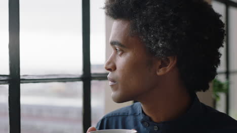 portrait-young-businessman-drinking-coffee-at-home-entrepreneur-enjoying-calm-relaxed-morning-looking-out-window-thinking-contemplative-trendy-afro-hairstyle