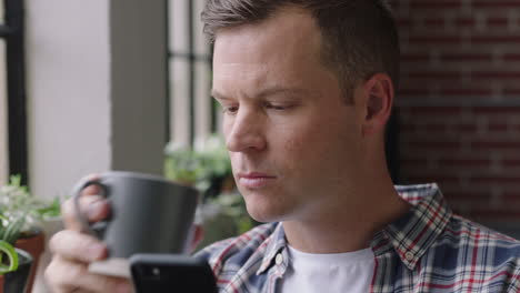 portrait-attractive-caucasian-man-using-smartphone-drinking-coffee-at-home-enjoying-relaxed-morning-browsing-messages-networking-texting-social-media-sharing-lifestyle-online-close-up