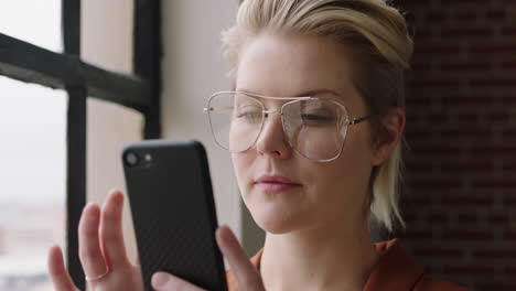 portrait-stylish-caucasian-business-woman-using-smartphone-at-home-browsing-messages-texting-on-mobile-phone-enjoying-relaxed-morning-networking-looking-out-window-planning-ahead-wearing-glasses