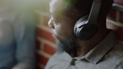 close-up-happy-black-businessman-chatting-to-friend-listening-to-music-wearing-headphones-enjoying-social-communication-brainstorming-student-sharing-study-ideas-relaxing-in-office-workplace
