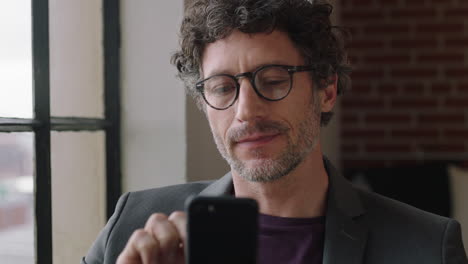 portrait-mature-businessman-using-smartphone-at-home-typing-email-messages-online-networking-on-social-media-enjoying-mobile-phone-communication-looking-out-window-planning-ahead-wearing-glasses