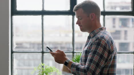 young-caucasian-man-using-smartphone-drinking-coffee-at-home-enjoying-relaxed-morning-browsing-messages-looking-out-window-texting-social-media-sharing-lifestyle-online-close-up