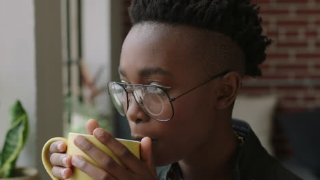 Porträt-Einer-Stilvollen-Jungen-Afrikanisch-amerikanischen-Studentin,-Die-Zu-Hause-Kaffee-Trinkt-Und-Aus-Dem-Fenster-Schaut,-Vorausschauend-Plant-Und-Einen-Entspannten-Lebensstil-Mit-Einer-Trendigen-Modebrille-Genießt