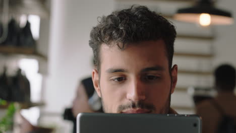 portrait-attractive-hispanic-man-using-digital-tablet-computer-in-cafe-drinking-coffee-browsing-online-reading-social-media-messages-on-mobile-device-enjoying-watching-entertainment