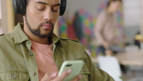 close-up-young-mixed-race-man-using-laptop-computer-browsing-online-messages-sharing-network-communication-student-enjoying-listening-to-music-checking-smartphone-social-media-in-modern-office