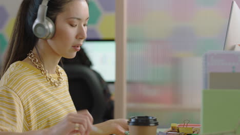close-up-beautiful-young-asian-woman-student-using-computer-brainstorming-working-on-creative-project-enjoying-study-in-colorful-modern-office-listening-to-music-wearing-headphones