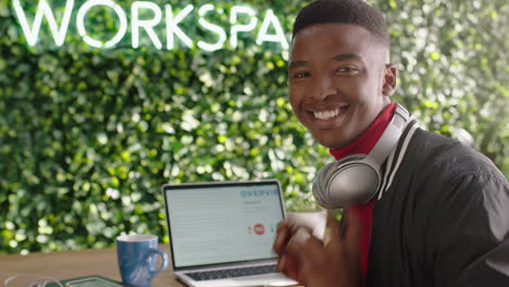 Porträt-Eines-Glücklichen-Afroamerikanischen-Geschäftsmannstudenten,-Der-Lächelt-Und-Eine-Erfolgreiche-Karriere-Im-Trendigen-Modernen-Büro-Genießt,-Indem-Er-Einen-Laptop-Computer-Verwendet-Und-Musik-Hört