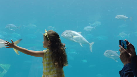 family-at-aquarium-father-taking-photo-of-daughter-using-smartphone-little-girl--enjoying-looking-at-fish-with-dad-sharing-fun-at-oceanarium-on-social-media