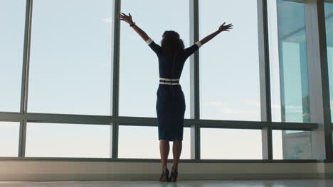 happy-busienss-woman-celebrating-success-with-arms-raised-looking-out-window-feeling-successful-in-office-confident-female-enjoying-achievement