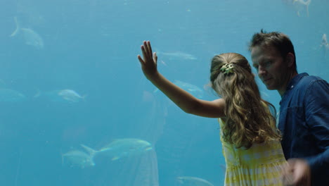 Glückliches-Mädchen-Mit-Vater-Im-Aquarium-Und-Blick-Auf-Fische,-Die-Im-Aquarium-Schwimmen.-Neugieriges-Kind,-Das-Neugierig-Das-Leben-Im-Meer-Beobachtet.-Vater-Bringt-Tochter-Im-Ozeanarium-Etwas-über-Meerestiere-Bei
