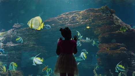 Junges-Mädchen-Im-Aquarium-Beobachtet-Fische-Beim-Schwimmen-Im-Aquarium.-Neugieriges-Kind-Hat-Spaß-Beim-Betrachten-Der-Farbenfrohen-Meereslebewesen-Im-Wasserlebensraum-Des-Ozeanariums