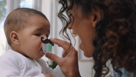 funny-baby-with-moustache-pacifier-happy-mother-having-fun-with-toddler-at-home-enjoying-silly-humor-with-child-sucking-on-dummy