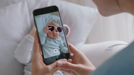 Mutter-Fotografiert-Ein-Lustiges-Baby-Mit-Sonnenbrille-Mit-Dem-Smartphone-Und-Genießt-Es,-Niedliche-Kleinkinder-Zu-Fotografieren,-Die-Ihren-Mutterschaftslebensstil-In-Den-Sozialen-Medien-Teilen