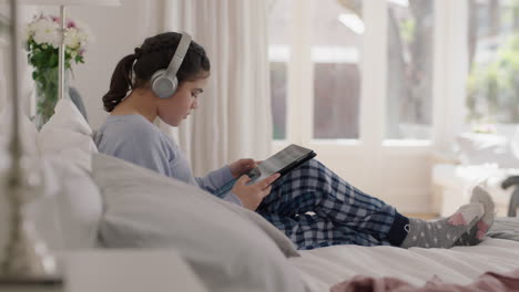 happy-teenage-girl-listening-to-music-wearing-headphones-browsing-online-using-tablet-computer-relaxing-on-bed-sharing-lifestyle-on-social-media-enjoying-weekend-morning