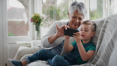 happy-little-boy-using-smartphone-showing-grandmother-how-to-use-mobile-phone-teaching-granny-modern-technology-intelligent-child-helping-grandma-at-home-4k