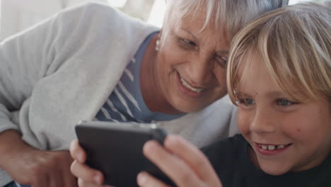 Glückliche-Großmutter,-Die-Einem-Kleinen-Jungen-Beim-Spielen-Auf-Dem-Smartphone-Zuschaut.-Kind,-Das-Zeigt,-Wie-Man-Ein-Mobiltelefon-Benutzt,-Und-Oma-Zu-Hause-Moderne-Technologie-In-4K-Beibringt
