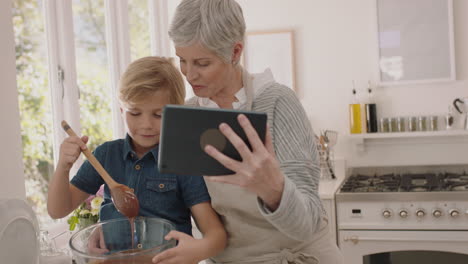Großmutter-Und-Kind-Nutzen-Tablet-Computer-Und-Unterhalten-Sich-Per-Video.-Kleiner-Junge-Mischt-Zutaten-Und-Teilt-Wochenendbacken-Mit-Oma.-Er-Genießt-Es,-Sich-Zu-Hause-Mit-Seinem-Enkel-über-Mobile-Technologie-Zu-Unterhalten