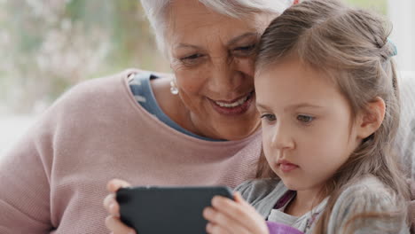 Kleines-Mädchen-Zeigt-Großmutter,-Wie-Man-Ein-Smartphone-Benutzt,-Bringt-Oma-Moderne-Technologie-Bei,-Intelligentes-Kind-Und-Hilft-Oma-Mit-Dem-Mobiltelefon-Zu-Hause-4k
