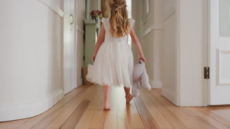 Süßes-Kleines-Mädchen,-Das-Durch-Das-Haus-Läuft-Und-Ein-Teddybär-Spielzeug-Hält,-Das-Ein-Hübsches-Weißes-Kleid-Trägt,-Rückansicht-4k