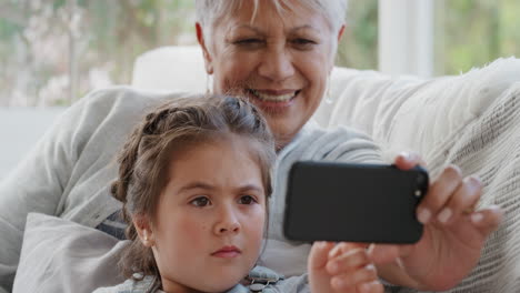 Kleines-Mädchen-Zeigt-Großmutter,-Wie-Man-Ein-Smartphone-Benutzt,-Bringt-Oma-Moderne-Technologie-Bei,-Intelligentes-Kind-Und-Hilft-Oma-Mit-Dem-Mobiltelefon-Zu-Hause-4k