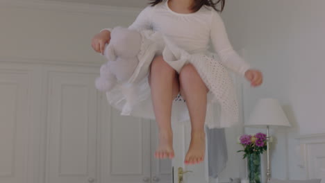 beautiful-little-girl-jumping-on-bed-holding-teddy-bear-having-fun-child-in-playful-mood-enjoying-weekend-morning-at-home