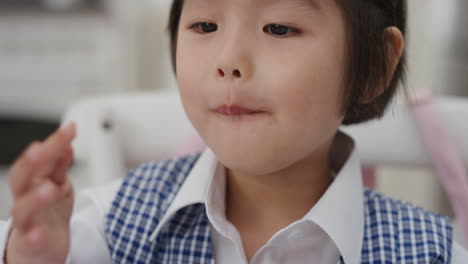 cute-little-asian-girl-eating-breakfast-enjoying-cereal-in-kitchen-getting-ready-wearing-school-uniform-4k