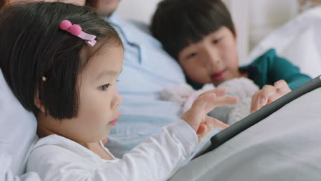 Glückliche-Asiatische-Familie,-Die-Zu-Hause-Einen-Tablet-Computer-Nutzt,-Mutter-Und-Vater-Mit-Kindern,-Die-Sich-Unterhaltung-Ansehen,-Ein-Spiel-Auf-Einem-Touchscreen-Gerät-Spielen,-Lernen,-Spaß-Haben-Und-Sich-Im-Bett-Entspannen,-4K-Videos