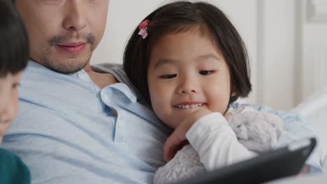 happy-asian-family-using-tablet-computer-at-home-mother-and-father-with-children-watching-entertainment-playing-game-on-touchscreen-device-learning-having-fun-relaxing-in-bed-4k-footage
