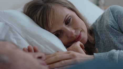 happy-young-couple-lying-in-bed-sharing-romantic-relationship-beautiful-woman-holding-husbands-hand-enjoying-intimacy-with-partner-relaxing-together-at-home-4k-footage
