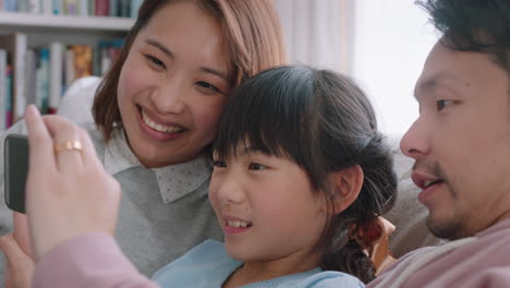 Glückliche-Asiatische-Familie,-Die-Zu-Hause-Einen-Video-Chat-Mit-Dem-Smartphone-Führt.-Mutter-Und-Vater-Mit-Tochter-Chatten-Gemeinsam-Auf-Dem-Mobiltelefon-Und-Winken-Mit-Der-Hand-Und-Genießen-Online-Kommunikation-In-4K-Videos