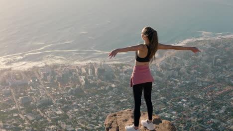 young-woman-with-arms-raised-on-mountain-top-celebrating-achievement-girl-on-edge-of-cliff-looking-at-beautiful-view-enjoying-travel-adventure-freedom