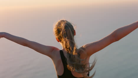 independent-woman-with-arms-raised-on-mountain-top-celebrating-achievement-girl-on-edge-of-cliff-looking-at-beautiful-view-at-sunset-enjoying-travel-adventure