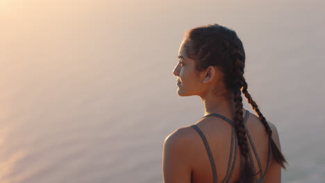 woman-on-mountain-top-looking-at-calm-view-of-ocean-at-sunset-girl-standing-on-edge-of-cliff-enjoying-travel-freedom
