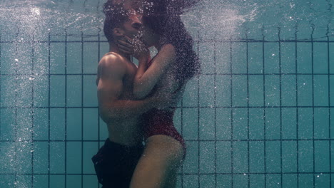 Verspieltes-Paar,-Das-Sich-Unter-Wasser-Im-Schwimmbad-Küsst.-Junge-Menschen-Genießen-Einen-Romantischen-Kuss.-Leidenschaftliche-Liebende-Sind-Im-Wasser-Untergetaucht,-Das-Mit-Blasen-Schwimmt,-Und-Genießen-Romantik