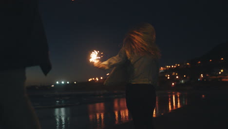 girl-friends-dancing-with-sparklers-on-beach-at-night-celebrating-new-years-eve-having-fun-dance-with-sparkler-fireworks-by-the-sea