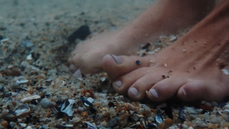 close-up-woman-feet-wiggling-toes-underwater-enjoying-gentle-beach-sea-sand-splashing-water-standing-on-seashells