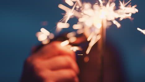 close-up-hand-lighting-sparkler-celebrating-new-years-eve-on-beach-at-night-watching-beautiful-sparks