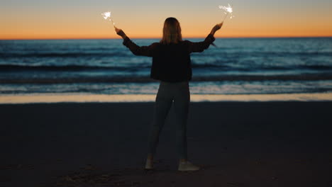 woman-dancing-with-sparklers-on-beach-at-sunset-celebrating-new-years-eve-girl-having-fun-dance-with-sparkler-fireworks-enjoying-independence-day-celebration-by-the-sea