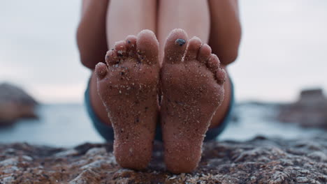 close-up-of-sandy-feet-young-woman-sitting-on-beach-barefoot-enjoying-summer-vacation