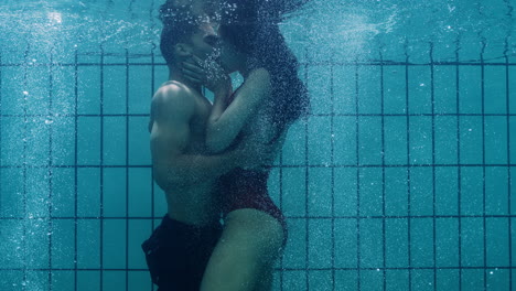 Romantisches-Paar,-Das-Sich-Unter-Wasser-Im-Schwimmbad-Küsst.-Verliebte-Junge-Menschen-Genießen-Innige-Küsse.-Liebende-Tauchen-Im-Wasser-Auf-Und-Schweben-Mit-Blasen-In-Leidenschaftlicher-Intimität